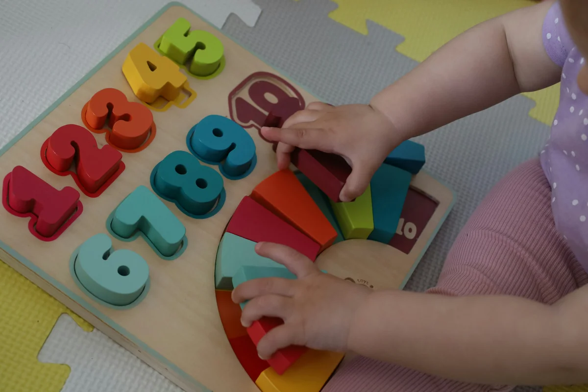 a little girl playing with a wooden toy - child development