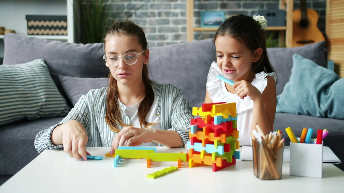 pretty woman playing blocks with cheerful daughter having fun at home bonding with child. Happiness, family activities and apartment concept. - family learning activities