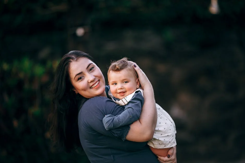 A joyful mother lovingly embraces her smiling baby in an outdoor setting. - parentchild communication