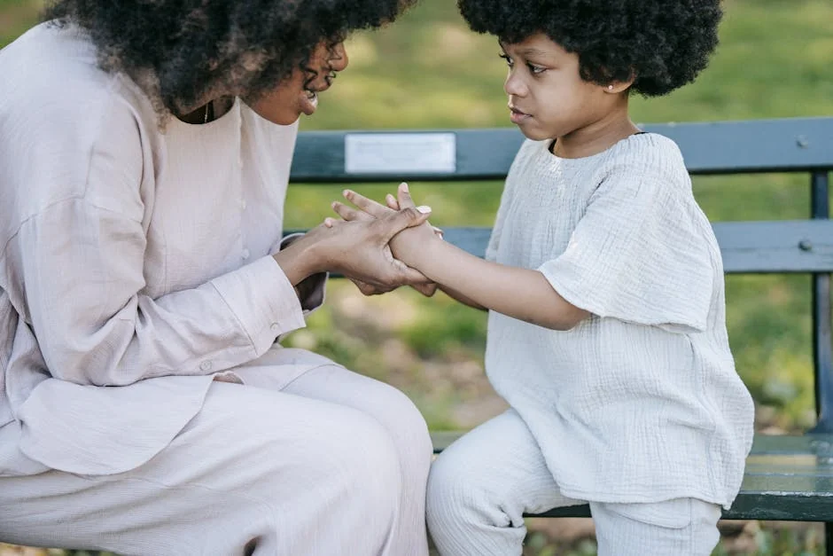 A mother and child sharing a heartfelt moment of connection and affection on a park bench outdoors. - parentchild communication