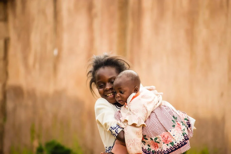 A heartwarming outdoor portrait of an older child holding a baby sibling, showcasing affection and joy. - family children care - Parenting tips